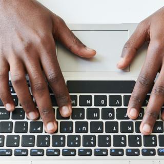 A person's hands prepared to type on a laptop keyboard.