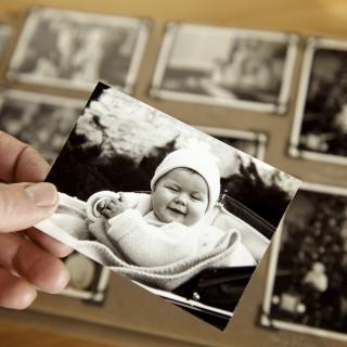 hand holding baby photo with photo album in the background