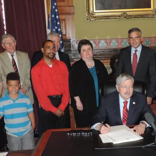 Iowa Gov. Terry Branstad signs a bill May 30, 2014, reforming the state’s laws HIV transmission laws.