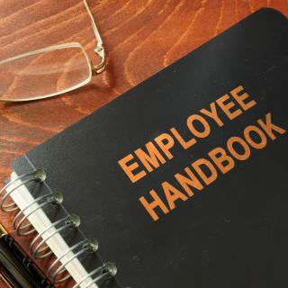Employee handbook on a wooden table and glasses. - Stock image