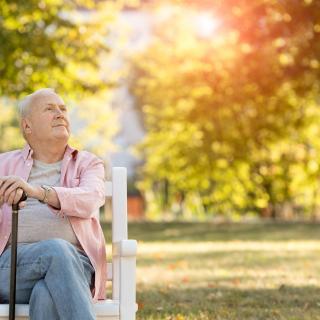 Senior man sitting on bench outdoors stock photo