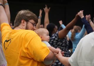 worshipers hold hands in the air at a 2016 General Assembly service