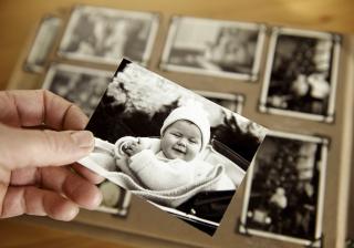 hand holding baby photo with photo album in the background