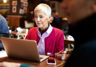 Mature woman working on a laptop at a coffee shop.