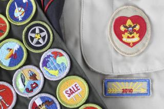close up of Boy Scout uniform shirt and merit badges on sash.