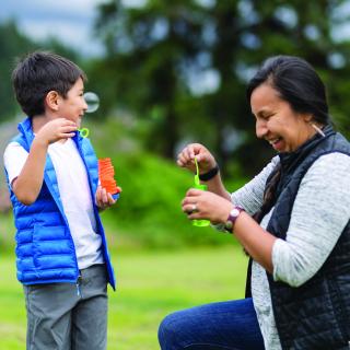 stock photo of indigenious adult and kid blowing bubbles together.