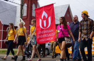 Youth carry a UUA banner 