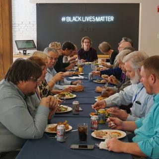 Members of the UUA board of trustees eating lunch in front of the new Black Lives Matter sign at the UUA.