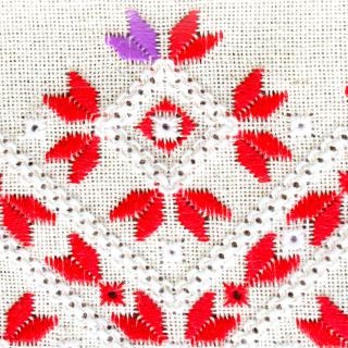 Red decorative stitching on white cloth with a small section of anomalous purple stitching