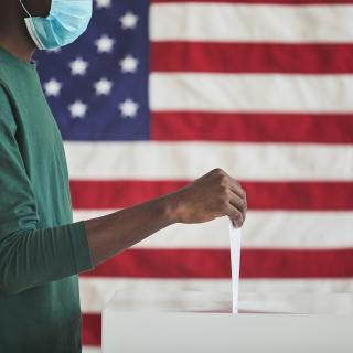 casting a vote with an American flag in the background