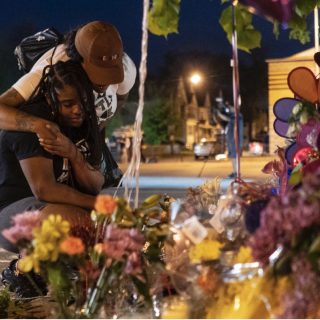 Pleazant Davis, 22, is comforted by Tasha Dixon, 35, at a memorial across the street from the store in Buffalo where Saturday's shooting occurred