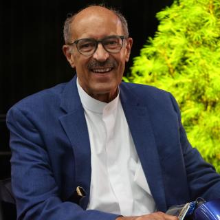 Rev. William G. Sinkford, a Black man in his 70s, smiles in a blue suit and white shirt