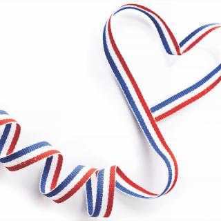 Blue, white, and red heart shaped ribbon against a white background.