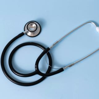Simple stethoscope on a pastel blue background.