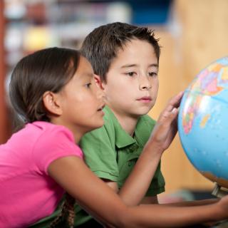 2 kids looking at a globe