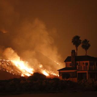 A wildfire threatens homes as it burns along the 101 Freeway Tuesday, Dec. 5, 2017, in Ventura, Calif.