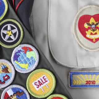 close up of Boy Scout uniform shirt and merit badges on sash.