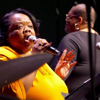 Cecilia Hayes sings during the Service of the Living Tradition at the 2018 General Assembly; Amanda M. Thomas conducts the choir in the background