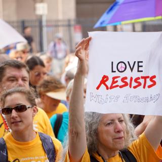 Marcher carries 'Love Resists' sign in second line parade at 2017 General Assembly