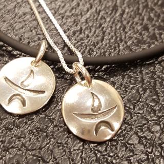 Photo of 2 silver flaming chalice pendants.