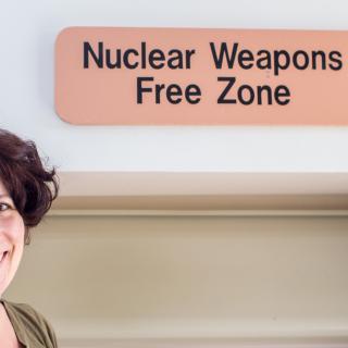 Liz James in front of her church's "Nuclear Weapons Free Zone" sign.