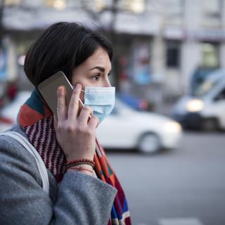 Young Woman With Face Mask Talking On The Phone. stock photo