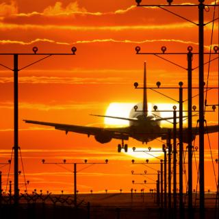 Stock photo of a plane landing at sunset.