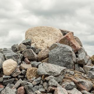 Pile of huge rocks and boulders under dark grey sky - Stock image
