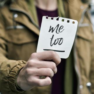 Person holding a slip of paper that says "Me too".