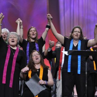 Choir members raise their hands during the Closing Ceremony of the 2012 General Assembly.