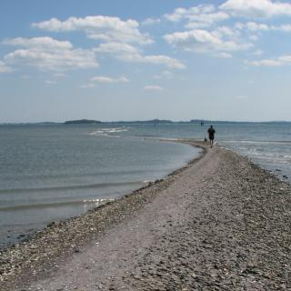 person walking on a gravel spit from an island in Boston Harbor
