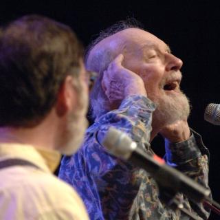 Pete Seeger singing at a microphone.