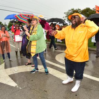 The Rev. Amy Carol Webb and Everette Thompson protest in the rain outside the Homestead detention facility near Miami