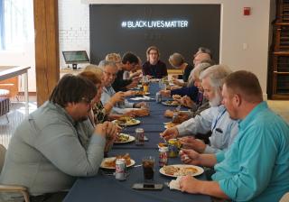 Members of the UUA board of trustees eating lunch in front of the new Black Lives Matter sign at the UUA.