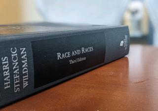 A legal textbook titled Race and Races sits on a wooden desk