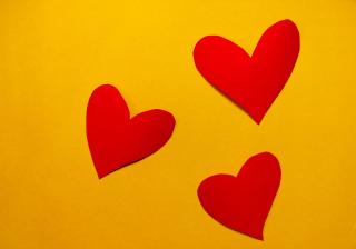 Three red hearts on a yellow background.