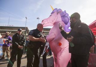 Police officers tell the Rev. Forrest Gilmore, who is dressed as a pink and purple unicorn, to leave before arresting him at a farmers' market in Bloomington, Indiana, where he and others have been protesting a vendor with ties to white supremacy groups