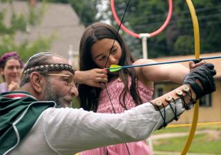 Helena Esparza gets an archery lesson from “Merlin” at KentHogwarts, a Harry Potter-themed summer camp run by the Unitarian Universalist Church of Kent, Ohio.