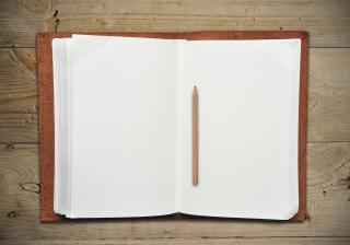  Open leather book with pencil on wooden table 