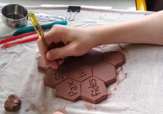 Rosalie Alff carves Latin words into clay that will become a chalice. 