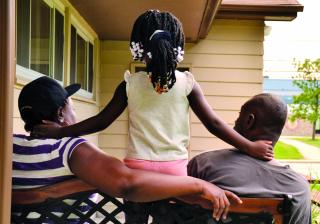 photo of the backs of asylum seekers and Chalice House residents Tania, Zizi, and Jerbo relaxing outside their home. 