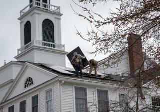 A side view of Bedford MA UU church looking up at installation of solar panels.
