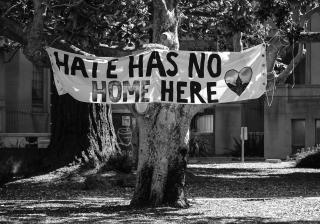 Banner hanging from a tree that says "Hate has no home here".