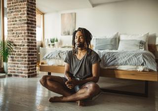 Stock photo of a young man practicing yoga at home. He is in bedroom and doing yoga, first thing in the morning.