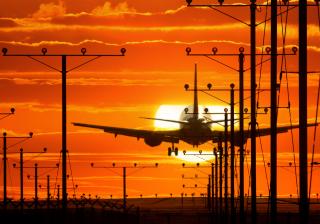 Stock photo of a plane landing at sunset.