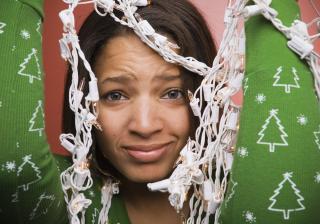 Stock image of woman holding up a tangle of holiday lights.