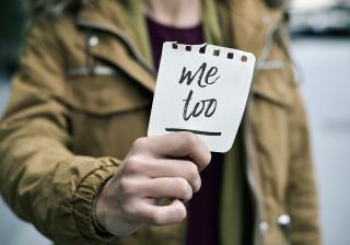 Person holding a slip of paper that says "Me too".