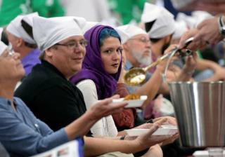 Thousands of participants at the Parliment of the World's Religions wear head covering and sit together as equals on the floor of the Salt Palace Convention Center on Friday while members of the Sikh religious community serve food at a traditional Langar.