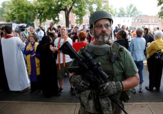 A member of a white supremacist militia stands in front of religious leaders, including UUA President Susan Frederick-Gray, who gathered to protest a rally of neo-Nazis and other white supremacists in Charlottesville, Virginia, on August 12, 2017. 