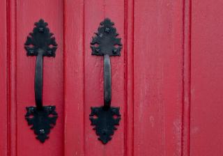 Two handles on a red church door.